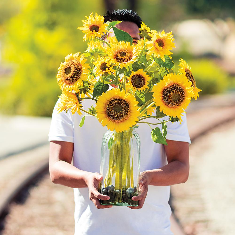 Artificial Faux Sunflower Bouquet in Glass Vase viewedoutsidein the sun so realistic